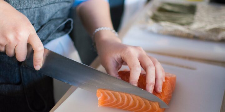 Person Slicing Meat On White Chopping Board