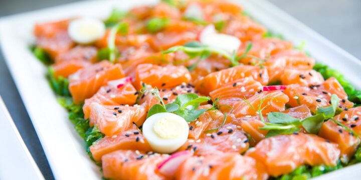 Salmon with greens and quail eggs on banquet table