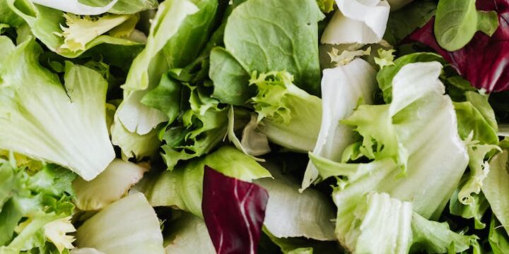 Top view of healthy lettuce and spinach salad served in white round bowl