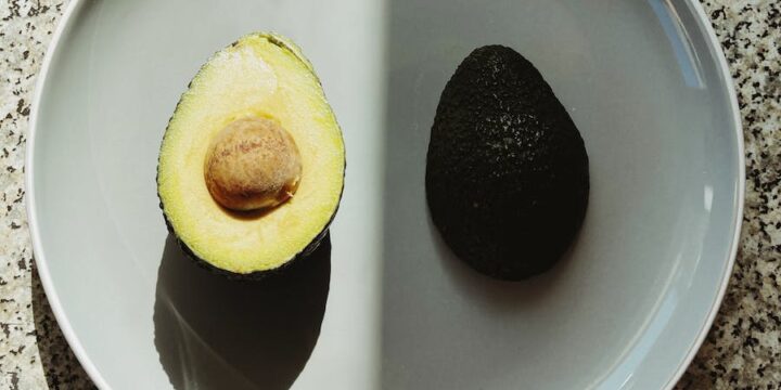 Top view of halves of fresh avocado placed on gray plate with half in shadow