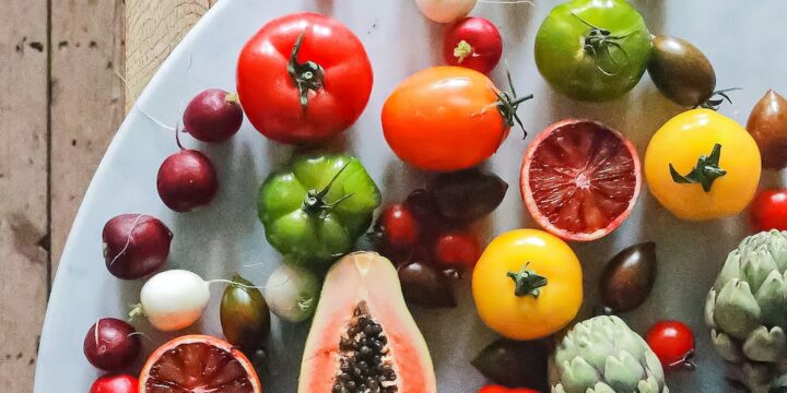 Top view of assorted exotic fruit with citrus and various vegetables of tomatoes and onions on round table