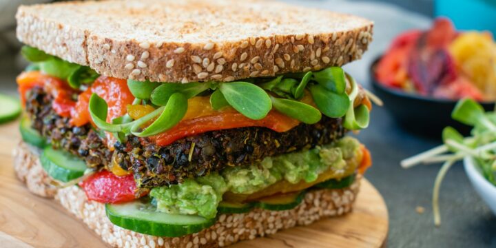 burger with tomato and lettuce on brown wooden round plate