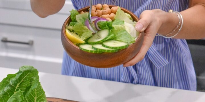 person holding green vegetable on brown ceramic plate