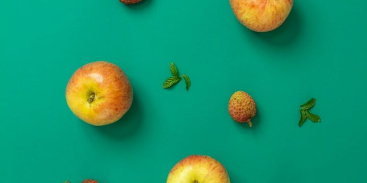 sliced apple and strawberries on pink surface